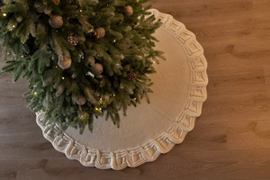 Detail of cream white cable knit Christmas tree skirt with decorative scalloped edges