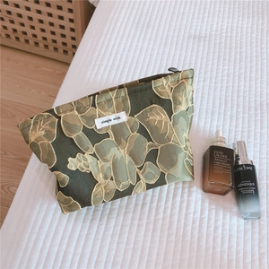 Detailed close-up of floral jacquard makeup bag with gold texture and logo label