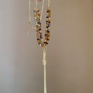 Detail view of ethnic beaded necklace featuring gold metal tassels and crystal beads