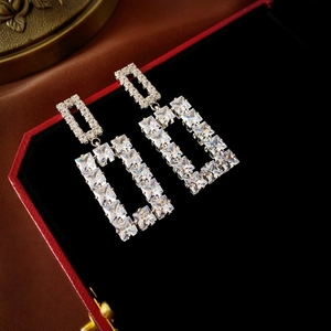 Detail of silver square geometric drop earrings with sparkling zircons in a jewelry box