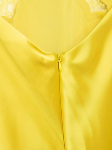 Détail de la robe en satin jaune avec fermeture éclair invisible et bordure en dentelle