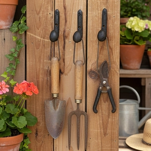 Industrial retro black cast iron wall hooks set displaying vintage gardening tools on wood