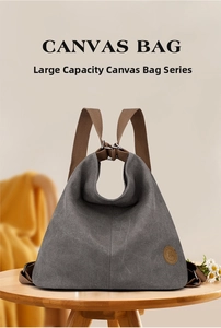 Dettaglio borsa in tela grigio scuro con manici marroni e logo in pelle su tavolo in legno