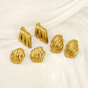 Detail shot of three pairs of 18K gold-plated stainless steel earrings on white silk fabric