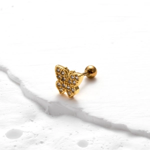 Golden butterfly stud earring with sparkling zircons on a white textured background