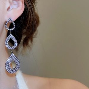 Detail of three-tier cascading purple rhinestone teardrop earrings on model