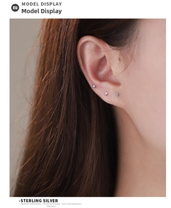 Close-up of three sterling silver stud earrings in pink, purple and white on ear