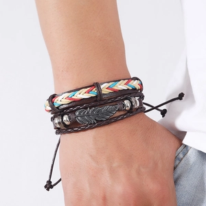 Close-up of multilayer leather bracelet with a metal feather charm and colorful braided cords
