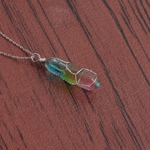 Close-up of rainbow crystal pendant with silver wire wrap on wooden background
