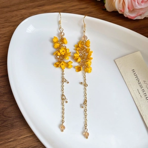 Detailed macro view of long yellow flower tassel earrings with delicate gold chain