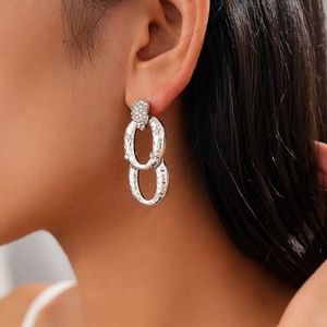 Close-up of vintage geometric silver earrings with sparkling zircon on a female model