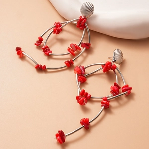Detail of silver drop earrings featuring red coral stone inlay and shell design
