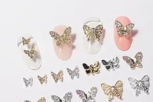 Detail of 3D mini butterfly nail charms with rhinestones and pearls on pink nails