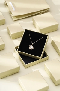 Detailed view of champagne gold jewelry box featuring a planet pendant necklace with pearls