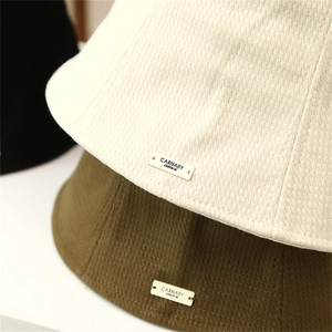 Détail de la texture gaufrée et étiquette logo sur chapeaux bob multicolores