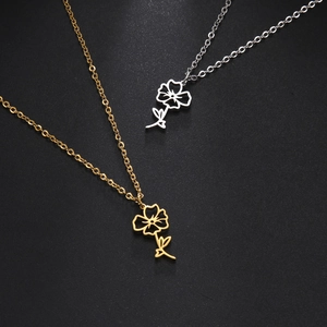 Close-up of hollowed-out flower pendants in gold and silver finish with fine chains