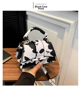 Detail view of mini cow print black PU leather handbag with adjustable strap and handle
