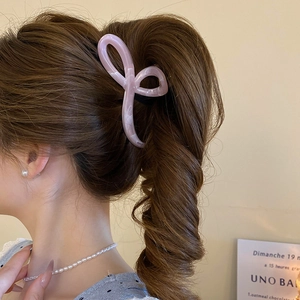 Detail view of pink marble claw clip styled on ponytail with a butterfly shape