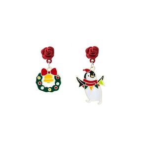 Detail of asymmetric Christmas earrings with red rose, wreath, bell and penguin charms