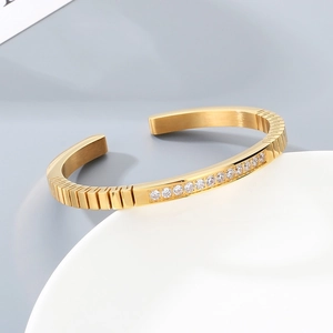 Detailed view of gold stainless steel bangle featuring inset white zircon stones and textures