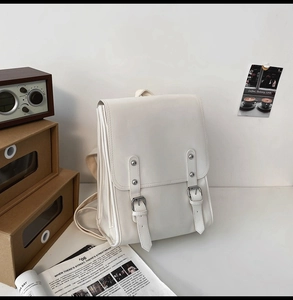 Detail view of a white vintage faux leather backpack with retro strap buckle closure