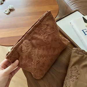Macro detail of brown suede embroidery pouch featuring delicate floral and rabbit patterns