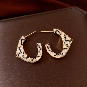 Detail shot of vintage 18K gold C-shaped earrings with leopard pattern zircons