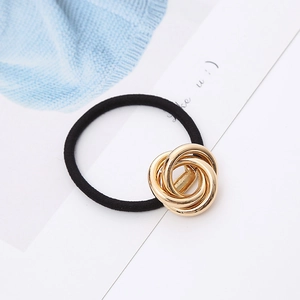 Minimalist elastic hair tie with gold metallic triple-loop ornament on white background