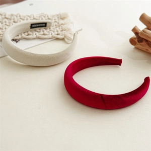 Macro shot of thick handmade velvet headbands in deep red and beige on a minimal background