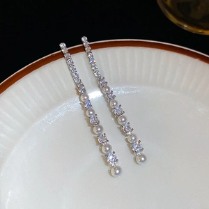 Détail de boucles d'oreilles à pampilles en argent avec zircon et perles sur céramique