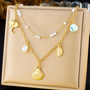 Detail of layered gold necklace with elephant shell and pearl charms on jewelry box