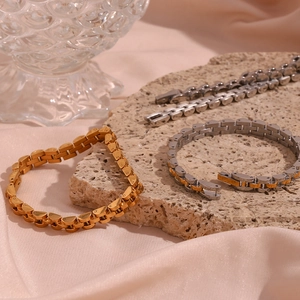 Detailed shot of 18K gold and silver watch band style link bracelets on luxury satin fabric
