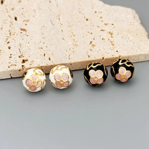 Detailed macro view of enamel round beads with gold floral patterns and pink accents