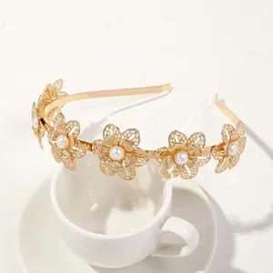 Detail of golden metal flower headband with delicate mesh petals and white center pearls