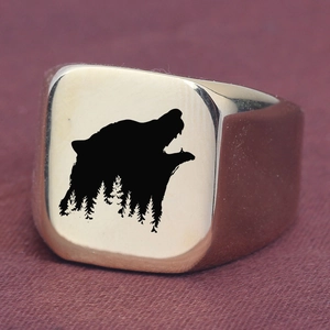 Detail shot of laser-engraved wolf and forest pattern on a square gold punk ring