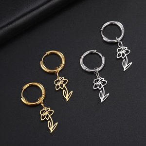 Detailed view of gold and silver hollow flower charms on earrings over black texture