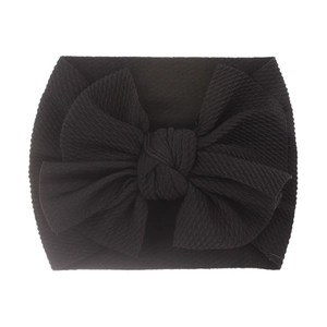 Soft black ribbed knit baby headband featuring a large bow on a pure white background