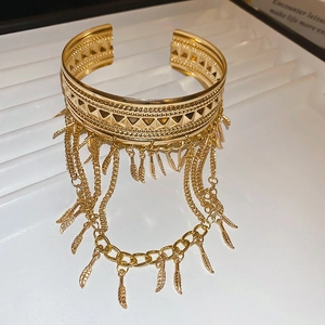 Gros plan d'un bracelet manchette doré avec des franges de chaînes et pendentifs feuilles