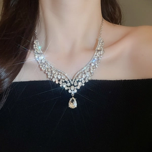 Detailed view of elegant silver V-shaped necklace with teardrop pendant worn by model