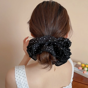 Detail of a large black polka dot mesh hair scrunchie with layered lace on a woman's hair