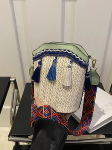 Detail of woven straw bucket bag with green leather trim and colorful geometric strap