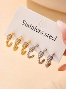 Detail of twisted stainless steel C-shape earrings set with sparkling zircon stones