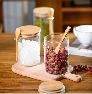 Macro shot of glass storage jars with bamboo lids and spoons on a wooden tabletop