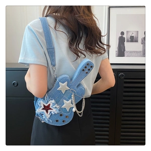 Dettaglio borsa a tracolla in denim a forma di chitarra con stelle argentate e catene in metallo