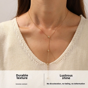 Close-up of a gold Y-shaped necklace with star pendants on a model wearing white knitwear