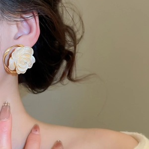Vue détaillée d'une boucle d'oreille dorée avec une rose 3D effet perle et strass brillant