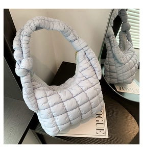 Close-up of light blue puffy quilted hobo bag with knotted handle and gold zipper detail