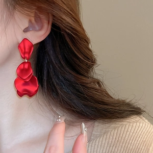 Close-up of elegant red triple-layered rose petal tassel earrings on a model