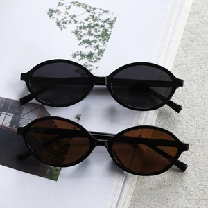 Close-up of black and dark brown oval sunglasses on a grey stone and magazine base
