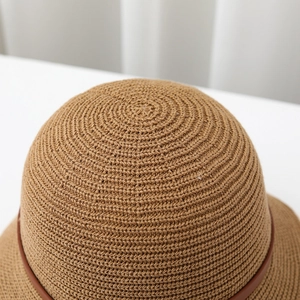 Detail view of the tight spiral weave and premium brown leather buckle on a straw bucket hat